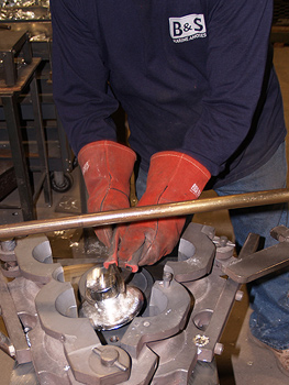 Man hand pouring molten zinc into an anode mold